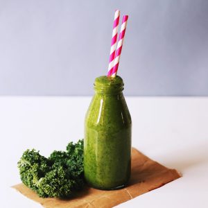 Google Juice. Green juice in a glass with two straws and kale.